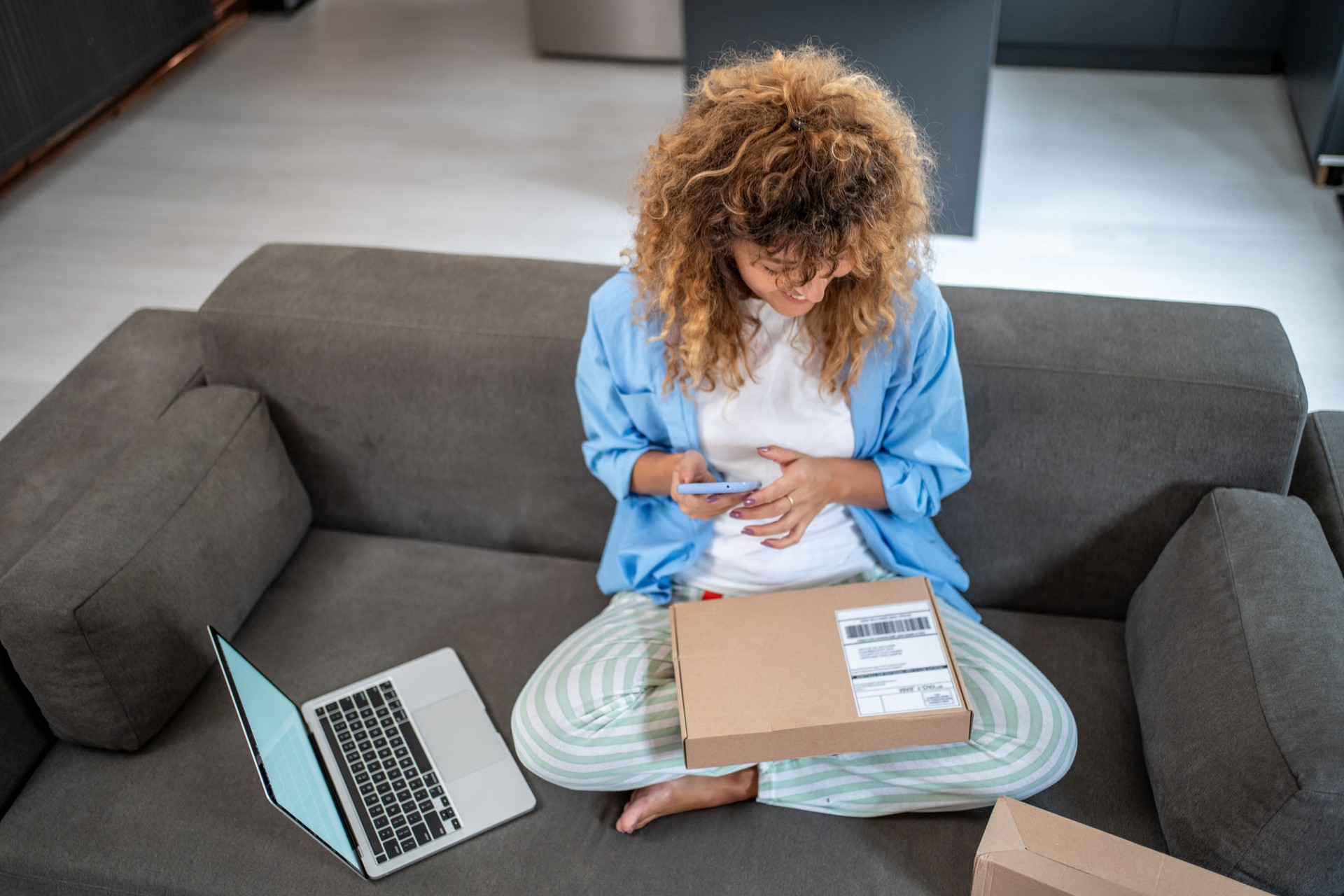 Young woman managing her online business from home sofa